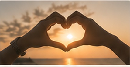 Hands forming a heart around the setting sun